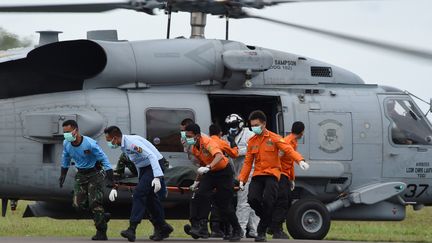 Des membres des &eacute;quipes de secours et de recherche indon&eacute;siennes ram&egrave;nent &agrave; terre le corps d'une victime du vol d'AirAsia, le 2 janvier 2014, &agrave; la base militaire de&nbsp;Pangkalan Bun (Indon&eacute;sie).&nbsp; (ADEK BERRY / AFP)