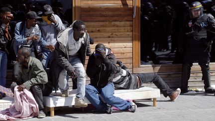 Des migrants se prot&egrave;gent du gaz lacrymog&egrave;ne lors de l'&eacute;vacuation de la biblioth&egrave;que Vaclav-Havel, rue Pajol, dans le 18e arrondissement de Paris, lundi 8 juin 2015. (FRANCOIS GUILLOT / AFP)