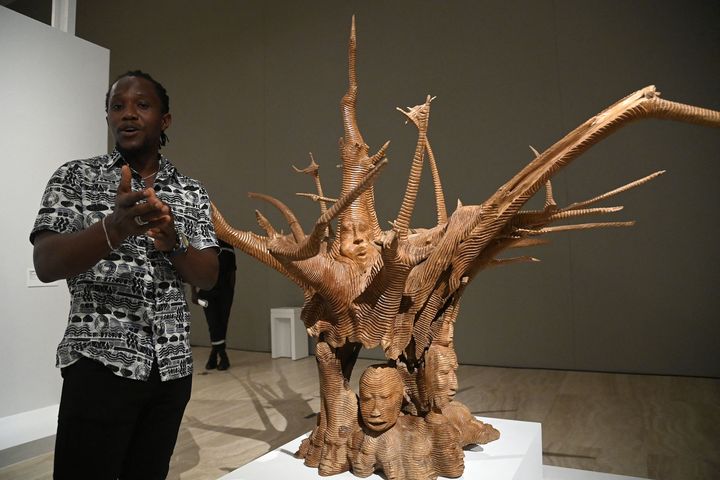 Le sculpteur béninois Degnon Toihen devant une de ses oeuvres exposée à&nbsp;"Art du Bénin d'hier et d'aujourd'hui, de la restitution à la révélation", samedi 19 février 2022 à Cotonou (Bénin). (PIUS UTOMI EKPEI / AFP)