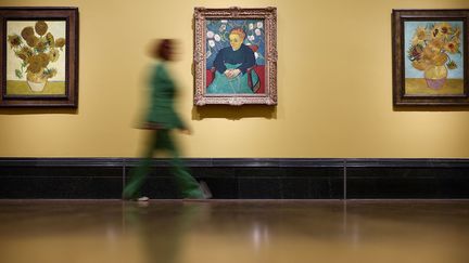 Un visiteur passe devant trois tableaux de Vincent Van Gogh à la National Gallery de Londres, en Grande-Bretagne, le 9 septembre 2024, lors d'un aperçu de la rétrospective 