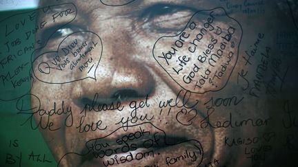 Une photo du visage de Nelson Mandela est recouverte d'inscriptions, &agrave; l'ext&eacute;rieur de sa maison de Soweto (Afrique du Sud), le 18 juillet 2013. (JEROME DELAY / AP / SIPA)