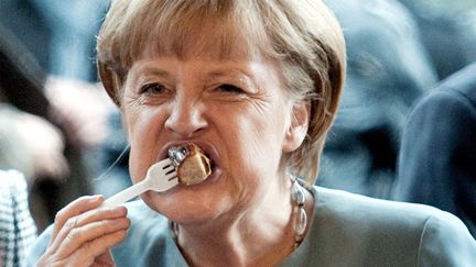 La chanceli&egrave;re allemande Angela Merkel d&eacute;guste une saucisse &agrave; Berlin (Allemagne), le 24 septembre 2012. (ROBERT SCHLESINGER / MAXPPP)