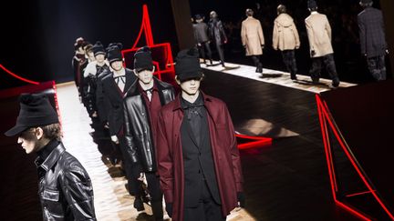 "Finalement, je prends un peu mes distances avec Christian Dior", explique Kris Van Assche. "Il y a un côté plus jeune, peut-être un peu moins bourgeois, pas du tout nostalgique"."J'ai eu envie du noir, de la nuit, de Berlin", poursuit le designer, qui a voulu jouer sur le contraste entre le côté sport du skate et le caractère sombre et poétique de la "new wave" des années 1980. Noir et rouge composent la palette. Les carreaux rouge et noir font des damiers sur des chemises de bûcheron, des doublures de vestes. Les poignets blancs sortent des manches d'une veste. Les pantalons sont tantôt courts et près du corps, tantôt baggy  A noter un sweat frappé d'un logo Dior, façon "tag". Le côté "do it yourself" de l'esthétique punk se retrouve sur des jeans peints à la main dans des tons gris, ou sur un manteau croisé classique dont  les broderies rouges en forme de carreaux s'effilochent. Un bonnet-casquette complète la silhouette. Pour Kris Van Assche, "l'actualité fait qu'on doit être plus fort pour faire rêver! J'aime penser que cela m'a poussé à faire une collection plus dynamique, plus jeune, plus mode", ajoute-t-il.
 (ETIENNE LAURENT/EPA/MaxPPP)