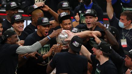 Les joueurs des Milwaukee Bucks célèbrent leur victoire face aux Atlanta Hawks autour du trophée de champion de la&nbsp;conférence Est, samedi 3 juillet 2021. (KEVIN C. COX / Getty Images via AFP)