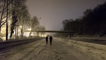 Des personnes marchent sur la N118, à hauteur de Vélizy-Villacoublay (Yvelines), complètement bloquée par la neige, le 6 février 2018.&nbsp; (SAMUEL BOIVIN / AFP)