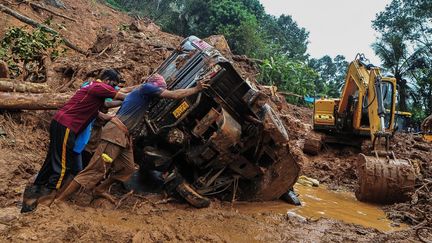 Des secouristes poussent un véhicule renversé coincé dans la boue et les débris sur le site d'un glissement de terrain causé par de fortes pluies à Kokkayar, dans l'État indien du Kerala, le 17 octobre 2021. (AFP)