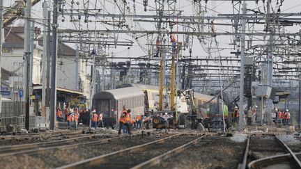 Des &eacute;quipes s'affairent aux travaux de d&eacute;sengagement des voies, le 13 juillet 2013, apr&egrave;s le d&eacute;raillement d'un train en gare de Br&eacute;tigny.&nbsp; (KENZO TRIBOUILLARD / AFP)