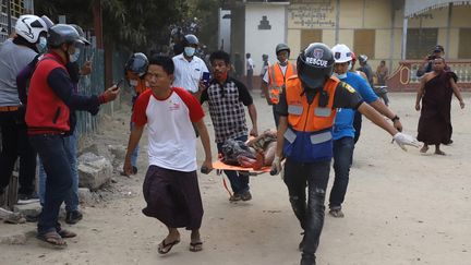 Un homme blessé porté par les secours lors d'une manifestation en Birmanie à Mandalay, le 20 février 2021. (AFP)