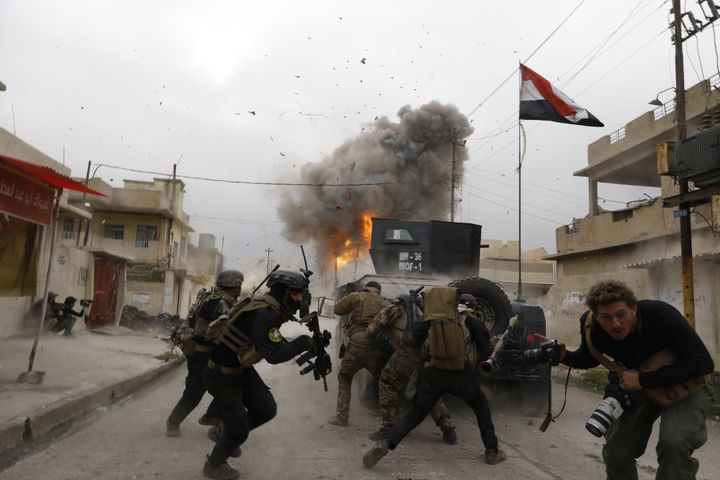 Irak, 2016. Mossoul. Explosion d’une voiture kamikaze à l’avant d’une colonne de la Golden Division. Au premier plan, le photographe Antoine Chauvel, fils de Patrick Chauvel. (PATRICK CHAUVEL)