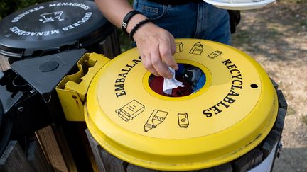 Une femme jette ses déchets recyclables dans une poubelle jaune, au Guerno (Morbihan), le 13 septembre 2020. (MARTIN BERTRAND / HANS LUCAS / AFP)