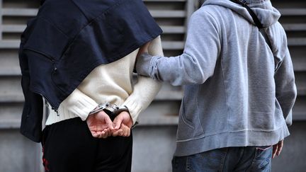 Un policier accompagne un suspect devant un juge d'instruction, le 14 octobre 2012, au palais de justice de Marseille (Bouches-du-Rh&ocirc;ne). (GERARD JULIEN / AFP)