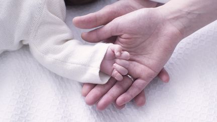 Des parents tiennent la main de leur nouveau-né, le 8 novembre 2013. (PHOTOALTO / ANNE-SOPHIE BOST / GETTY IMAGES)