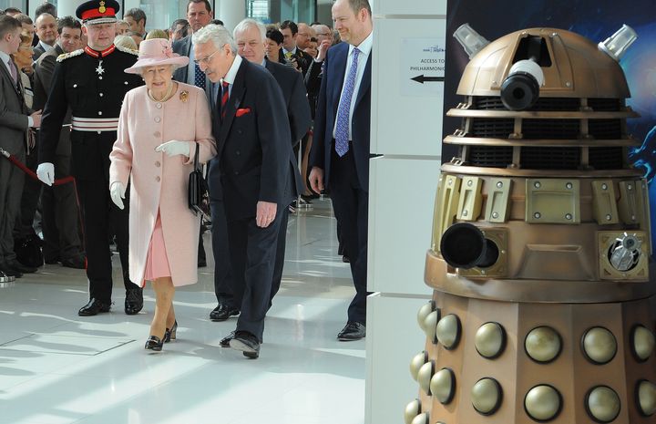 La reine d'Angeleterre Elizabeth II visite MediaCity, &agrave; Salford (Royaume-Uni), le 23 mars 2012. A droite, un Dalek guette. (ANDREW YATES / AFP)