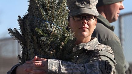 Une soldate de l'arm&eacute;e am&eacute;ricaine tient son sapin de No&euml;l re&ccedil;u en cadeau &agrave; Fort Carson (Colorado), le 7 d&eacute;cembre 2011. (JOHN MOORE / GETTY IMAGES)