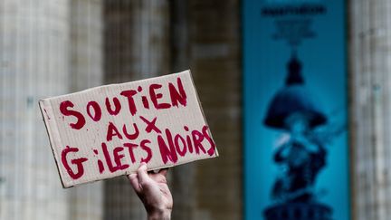 Une pancarte "soutien aux 'gilets noirs'" brandie devant le Panthéon occupé, le 12 juillet 2019, par des sans-papiers.&nbsp; (ESTELLE RUIZ / NURPHOTO / AFP)