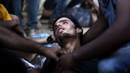 Un homme s'effondre alors que des policiers tentent de disperser les migrants qui attendent d'être enregistrés par la police à Lesbos, le 5 septembre 2015. Plus de 230.000 réfugiés sont arrivés en Grèce par la mer cette année, une augmentation énorme par rapport aux 17.500 de la même période de 2014. (ANGELOS TZORTZINIS / AFP)