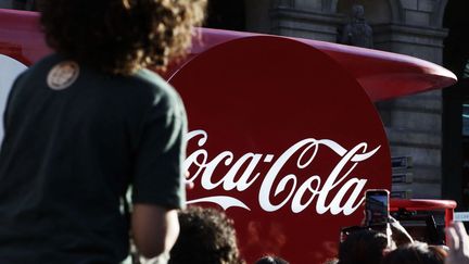 A Coca-Cola advertising vehicle in front of the Olympic flame, in Paris, July 14, 2024. (NICOLAS RONGIER / HANS LUCAS / AFP)