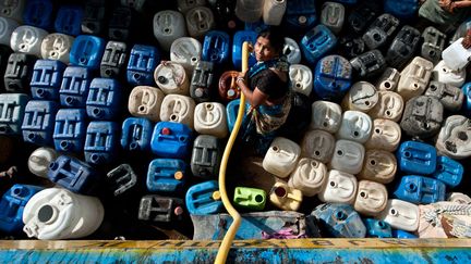 Une femme remplit des bidons d'eau pr&egrave;s de New Delhi (Inde), alors que qu'une canicule meurtri&egrave;re s'est abattue sur l'est du pays depuis une dizaine de jours, le 16 juin 2012. (MANAN VATSYAYANA / AFP)