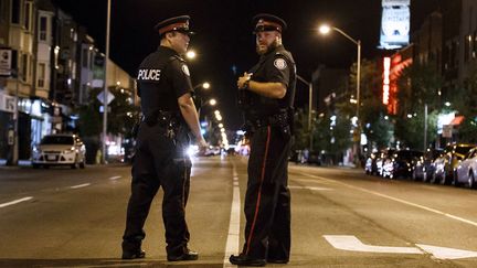 Deux policiers sur les lieux d'une fusillade à Toronto (Canada), le 23 juillet 2018.&nbsp; (COLE BURSTON / AFP)