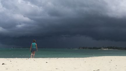 Une femme marche sur la plage de Nassau, aux Bahamas, alors qu'une tempête arrive, le 12 septembre 2019. (ANDREW CABALLERO-REYNOLDS / AFP)