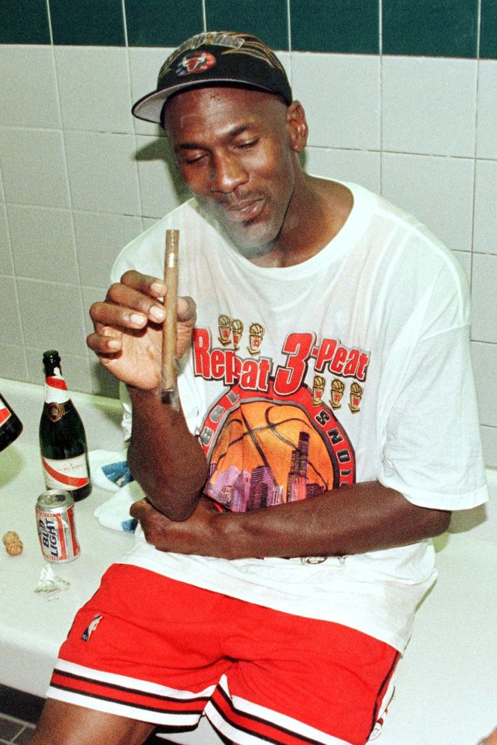 Michael Jordan et son habituel cigare dans les vestiaires, après son sixième titre NBA avec les Chicago Bulls, le 14 juin 1998 à Salt Lake City. (MIKE NELSON / AFP)