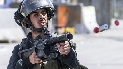 Un garde fronti&egrave;re isra&eacute;lien tire une cartouche de gaz lacrymog&egrave;ne lors d'affrontements avec des jeunes Palestiniens pr&egrave;s de Ramallah (Palastine), le 15 mai 2014. (JACK GUEZ / AFP)