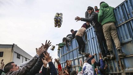 Les membres d'une organisation humanitaire turque distribuant des vivres aux réfugiés syriens installés dans un camp près du passage frontalier de Bab al-salam, non loin de la ville d'Azaz, le 13 février 2016. (Fatih Aktas / ANADOLU AGENCY/AFP)