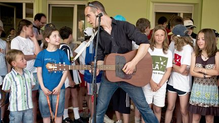 L'auteur-compositeur Guillaume Aldebert chante devant des élèves de l'école de&nbsp;Naisey-les-Granges (Doubs), le 24 mai 2009. (JEFF PACHOUD / AFP)