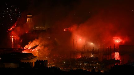 Le Vieux Port de Marseille se pare de rouge avec des fumigènes allumés sur tout le littoral pour célébrer le 26 mai 2023 les 30 ans de la victoire de l'OM en Ligue des champions (NICOLAS TUCAT / AFP)