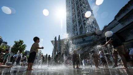 Des enfants se rafraîchissent dans des fontaines, à Tokyo, au Japon, le 16 juillet 2023. (RICHARD A. BROOKS / AFP)