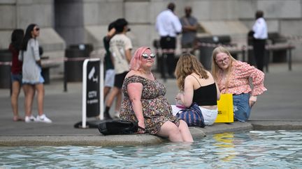 Des passants se rafraichissent dans une fontaine à Trafalgar Square à Londres (Grande-Bretagne), le 13 juillet 2022. (JUSTIN TALLIS / AFP)