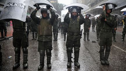 Des policiers se prot&egrave;gent de la pluie avec leurs boucliers lors d'une manifestation &agrave; Bogota (Colombie), le 23 avril 2012. (GUILLERMO LEGARIA / AFP)