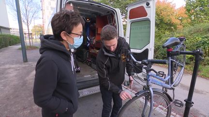 Alexis, un salarié de Happy-Cyclette, est venu réparer le vélo de Christelle au pied de son immeuble. (V. Bars / France Télévisions)