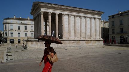 Une femme se protège du soleil, à Nîmes (Gard), le 19 juillet 2023. (SYLVAIN THOMAS / AFP)