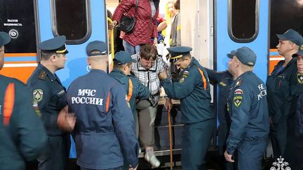 Des agents gouvernementaux aident des personnes évacuées des colonies frontalières de la région de Koursk à leur arrivée à la gare d'Oryol (Russie), le 9 août 2024. (MINISTERE DES SITUATIONS D'URGENCE RUSSE / AFP)