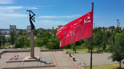 Un drapeau soviétique flotte au dessus d'un mémorial consacré à la Second Guerre mondiale à Kherson (Ukraine), le 20 mai 2022. (ANDREY BORODULIN / AFP)