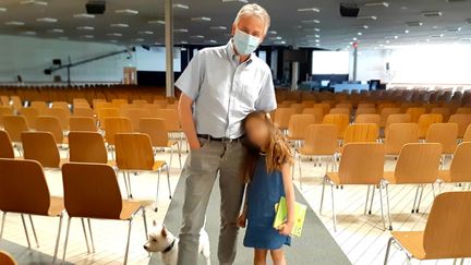 Le pasteur Samuel Peterschmitt, sa petite fille et son fox terrier irlandais dans la salle de prière de&nbsp;l’Eglise Porte ouverte chrétienne, à Mulhouse, qui peut en principe accueillir 2 400 personnes. (VALENTIN DUNATE / RADIO FRANCE)