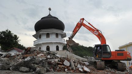 Une pelleteuse déblaie des gravas à côté de la mosquée Quba, endomagée par le séisme qui a touché Pidie Jaya, dans la province d'Aceh en Indonésie, le 7 décembre 2016. Des dizaines de milliers de personnes ont été déplacées par le tremblement de terre, qui a fait fait plus de 100 morts. (CHAIDEER MAHYUDDIN / AFP)