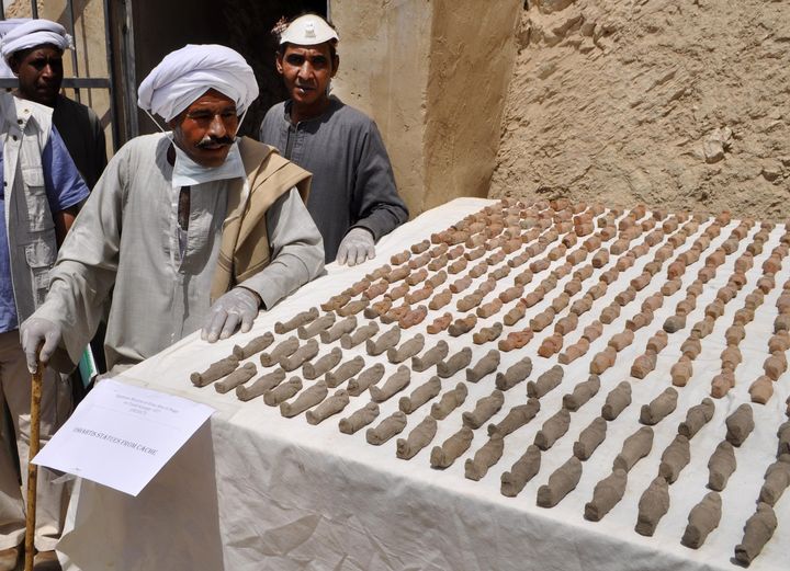 Des membres d'une équipe archéologique égyptienne inspectent des statuettes, le 18 avril 2017, dans la&nbsp;nécropole de Dra Abou el-Naga, près de Louxor (Egypte). (STRINGER / AFP)