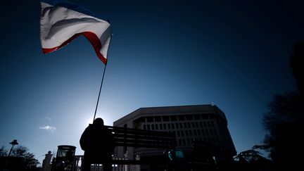 Un homme brandit le drapeau de la Crim&eacute;e, devant le Parlement de l'ancienne p&eacute;ninsule ukrainienne &agrave; Simf&eacute;ropol, le 18 mars 2014. (FILIPPO MONTEFORTE / AFP)