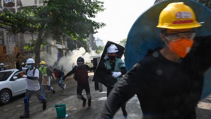 Des manifestants fuient&nbsp;les gaz lacrymogènes de la police anti-émeute lors d'une manifestation contre le coup d'Etat militaire, à&nbsp;Rangoun&nbsp;(Birmanie), le 2 mars 2021. (STR / AFP)