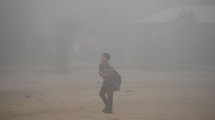 Un enfant marche dans une rue de New Delhi, envahie par une épaisse brume de pollution. (SAJJAD HUSSAIN / AFP)