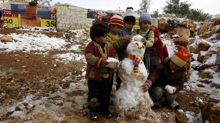 De jeunes r&eacute;fugi&eacute;s syriens font un bonhomme de neige, le 12 d&eacute;cembre 2013, dans le camp de Baaloul (Liban). (MAHMOUD ZAYYAT / AFP)