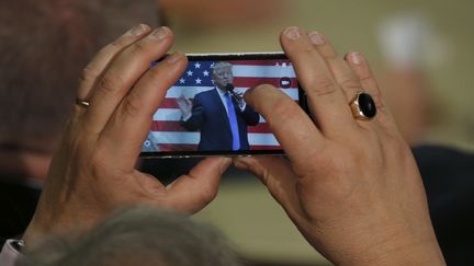 Un homme prend un cliché de Donald Trump, le 6 octobre 2016 à Sandown (Etats-Unis). (MARY SCHWALM / AFP)