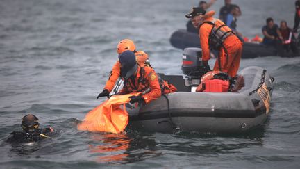 Des plongeurs remontent à la surface des sacs remplis de débris et de restes humains après la disparition du Boeing 737-500 de Sriwijaya Air, le 11 janvier 2021 au large de Jakarta. (DEMY SANJAYA / AFP)