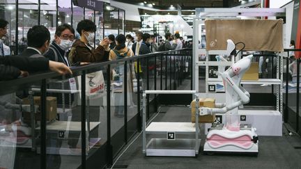 Des visiteurs de l'IRex, à Tokyo observe un robot. (NICOLAS DATICHE / LIGHTROCKET)