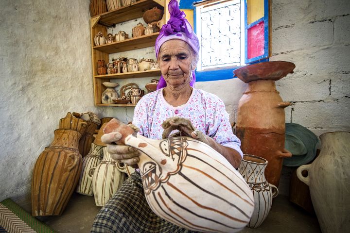 La potière marocaine Aicha Tabiz, également connue sous le nom de Mama Aicha, tient l'une de ses œuvres près du village d'Ourtzagh, au pied des montagnes du Rif, le 12 juin 2019. (FADEL SENNA / AFP)