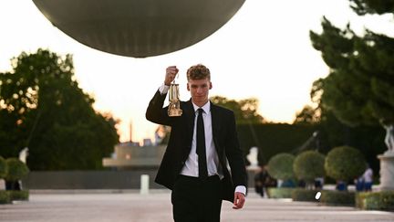 Le nageur Léon Marchand récupère la flamme olympique au jardin des Tuileries, lors de la cérémonie de clôture des Jeux olympiques de Paris 2024, le 11 août 2024. (LOIC VENANCE / AFP)