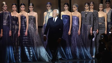 La journée s'est terminée avec le défilé Giorgio Armani Privé. La collection dominée par un dégradé de bleus très doux renvoie aux années 20. Les mannequins ont les cheveux retenus dans un foulard. Elles ne portent que du long (jupes, robes, pantalons), qui peut être transparent ou fendu le long de la jambe et privilégient l'évasé. Il y a beaucoup d'imprimés : des bandes horizontales, des motifs géométrique. La femme pioche chemises et vestes dans la garde-robe de son homme, ce qui la rend encore plus féminine, avec un air bohémien chic. Le couturier propose aussi des robes "très princesse", bustier, dos nu ou à fines bretelles croisées, brillantes, avec paillettes, cristaux, microperles et strass brodés. Après le défilé, dans le cadre de l'événement "One Night Only Paris", les invités ont pu (re)découvrir 80 pièces de précédentes collections Giorgio Armani et Giorgio Armani Privé. L'exposition « Eccentrico » présente une sélection d’accessoires : bijoux, sacs, souliers, chapeaux ainsi que la collection de parfums Armani/Privé en hommage au savoir-faire de la haute parfumerie. Elle est ouverte au public jusqu'au 26 janvier et se tient au Palais de Tokyo. 
 (MIGUEL MEDINA / AFP)