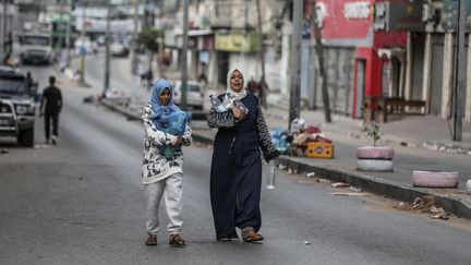 Des Palestiniennes portent des bouteilles d'eau, le 17 octobre 2023, alors que l'aide humanitaire est bloquée à la frontière égyptienne. (ALI JADALLAH / ANADOLU)